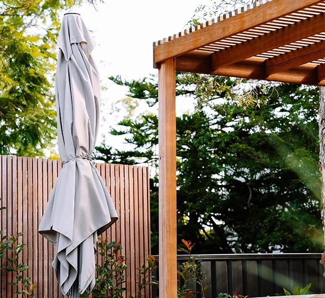 timber pergola next to backyard umbrella
